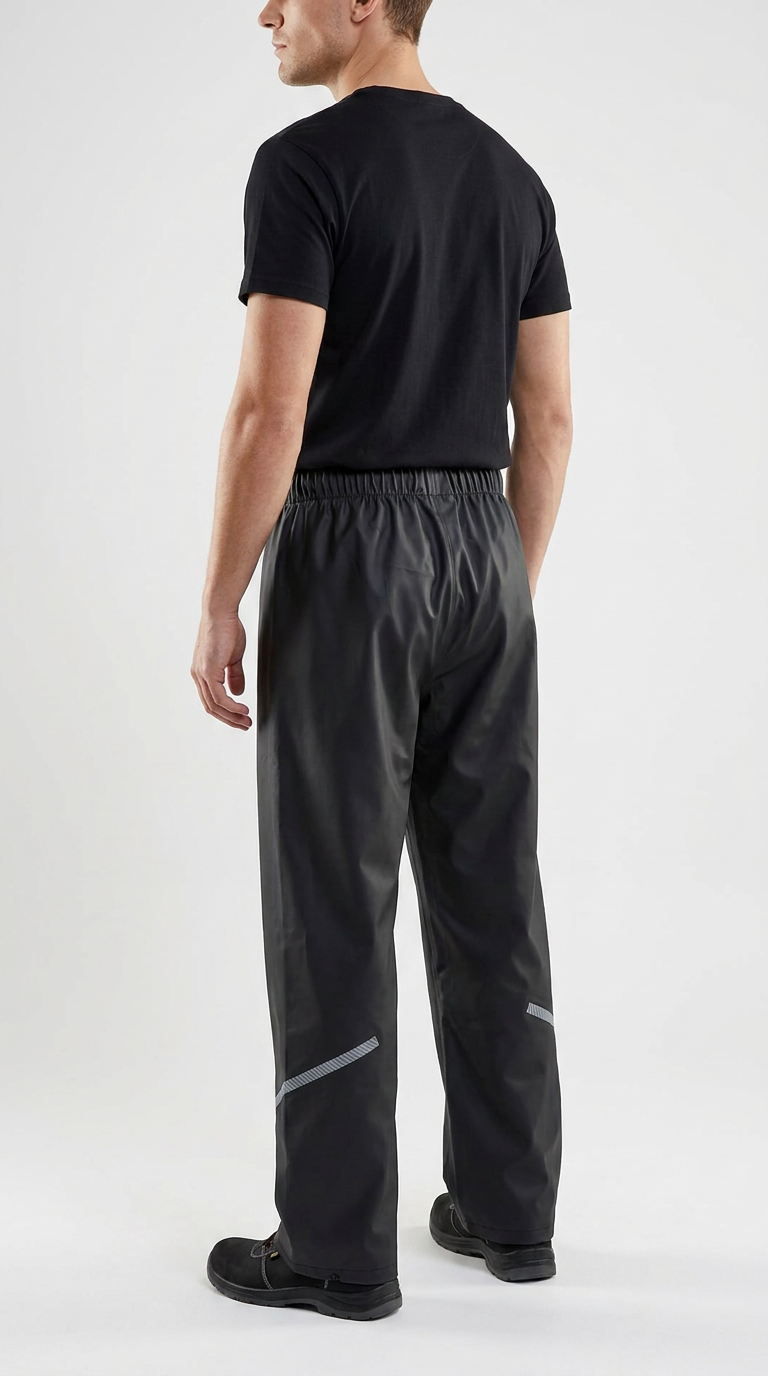 Mand set bagfra iført sort t-shirt og sorte regnbukser med refleksdetaljer mod en hvid baggrund.