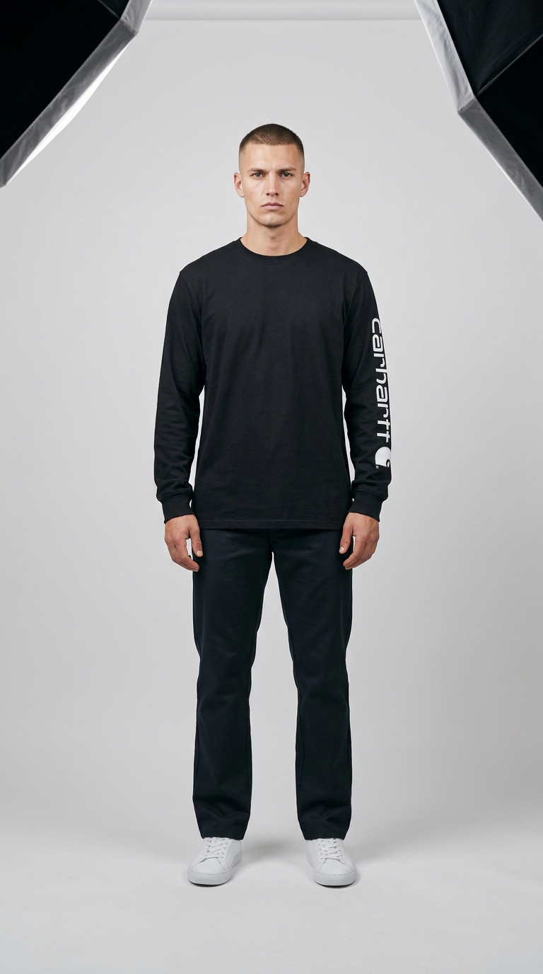Mand iført sort langærmet Carhartt-trøje med logo på ærmet, mørke bukser og hvide sneakers i et fotostudie.