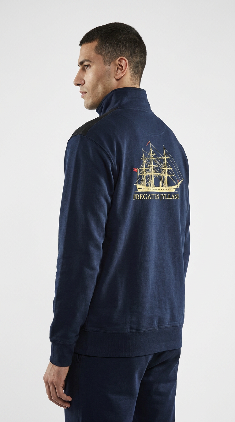 Mand i en mørkeblå sweatshirt med guldtryk af Fregatten Jylland på ryggen.