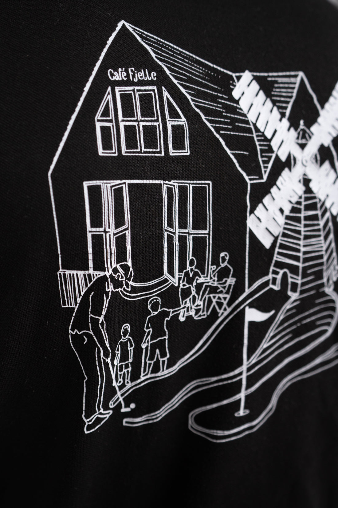 Sort T-shirt til Cafe Fjelle med håndtegnet rygdesign af caféhuset