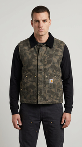 Mand iført en camouflage Carhartt-vest og sort langærmet trøje mod en grå baggrund.