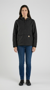 Kvinde iført en sort Carhartt anorak og blå jeans mod en enkel grå baggrund.