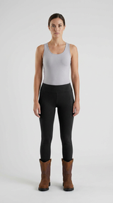 Kvinde i grå tanktop, sorte leggings og brune arbejdsstøvler mod en hvid baggrund.