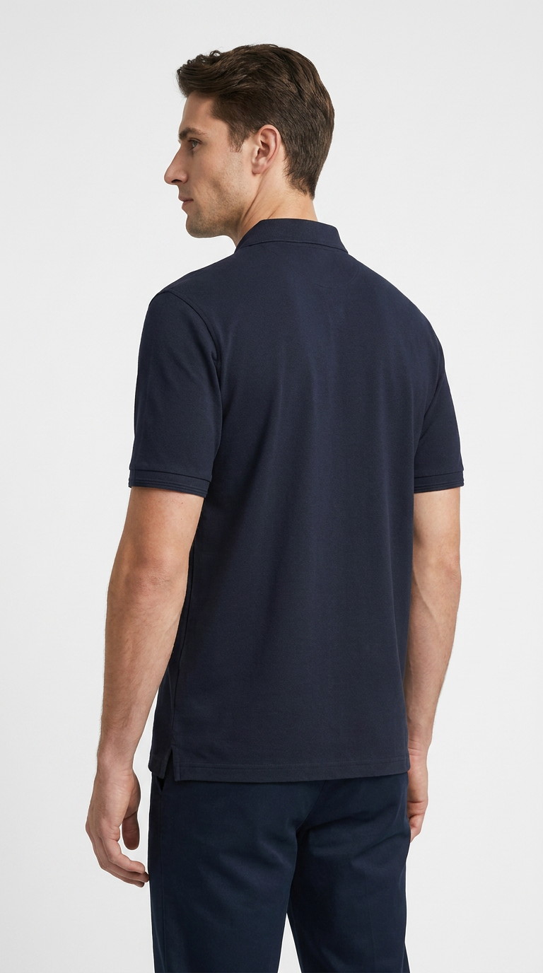 Mand set bagfra iført en mørkeblå kortærmet polo shirt mod en hvid baggrund.