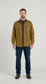 Mand iført en brun Carhartt-skjortejakke, mørkeblå jeans og brune støvler mod en hvid baggrund.