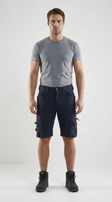 Mand i grå t-shirt, mørkeblå arbejdsshorts og sorte arbejdsstøvler på hvid baggrund.