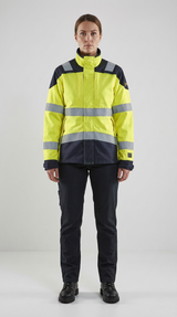 Kvinde i gul og mørkeblå high-visibility arbejdsjakke med reflekser og mørkeblå bukser.