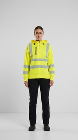 Kvinde i gul high-vis hættetrøje med reflekser og sorte bukser på en lys baggrund.