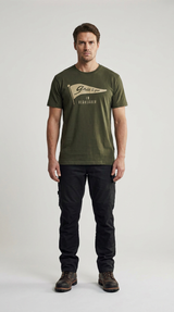 Mand i grøn t-shirt med logo, sorte arbejdsbukser og brune støvler på en lys baggrund.