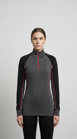 Kvinde i grå og sort base layer med rød lynlås og kontrastsyninger mod en neutral baggrund.