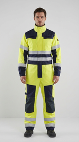 Mand i gul og mørkeblå high-visibility kedeldragt med refleksstriber og knæpuder mod en lys baggrund.