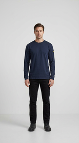 Mand i mørkeblå langærmet t-shirt og sorte bukser foran en lys grå baggrund.