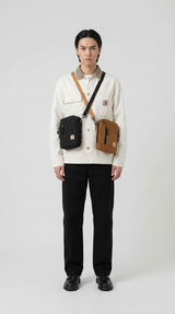 Mand i hvid Carhartt-jakke med to skuldertasker i sort og brun mod en neutral baggrund.