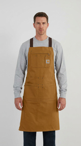 Mand iført et brunt Carhartt-arbejdsforklæde med flere lommer over en grå langærmet trøje.