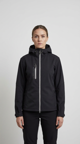 Kvinde iført en sort softshell-jakke med hætte og sølvfarvet lynlås mod en lys grå baggrund.