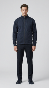 Mand i marineblå sweatshirt med lynlås, matchende bukser og sneakers mod en lys baggrund.