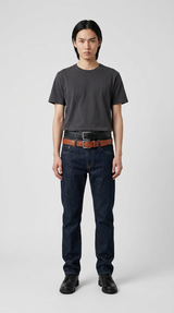 Mand i grå t-shirt, mørkeblå jeans med to bælter og sorte sko mod en lys baggrund.