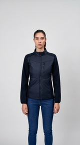 Kvinde i mørkeblå hybridjakke og blå jeans mod en lys grå baggrund.