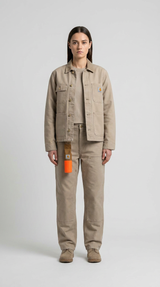 Kvinde i beige Carhartt-arbejdstøj bestående af jakke og bukser mod en lys grå baggrund.