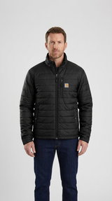 Mand iført en sort quiltet Carhartt-jakke og blå jeans mod en hvid baggrund.