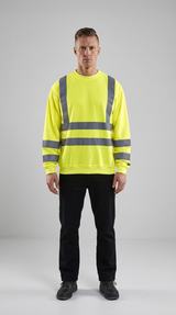 Mand i neongul sweatshirt med refleksstriber og sorte bukser på en grå baggrund.