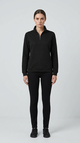 Kvinde i sort sweatshirt med lynlås og sorte jeans foran en lys grå baggrund.