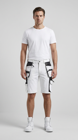 Mand i hvid t-shirt, hvide arbejdsshorts med sorte lommer og hvide støvler mod en grå baggrund.