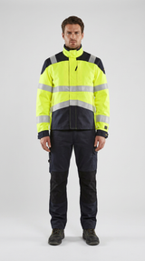 Mand i gul og marineblå high-vis arbejdsjakke med reflekser og matchende bukser på en lys baggrund.