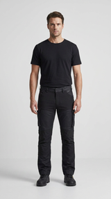 Mand iført sort t-shirt og sorte arbejdsbukser mod en lys baggrund.