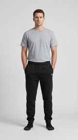 Mand i grå t-shirt og sorte joggingbukser på en lys baggrund.