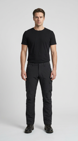 Mand i sort t-shirt og sorte arbejdsbukser stående mod en lys grå baggrund.
