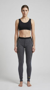 Kvinde i sort sports-bh og grå mønstrede leggings mod en ensfarvet baggrund.
