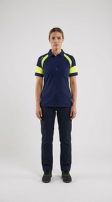 Kvinde i mørkeblå poloshirt med neon-gule detaljer og matchende arbejdsbukser.