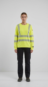 Kvinde i en neongul sweatshirt med refleksstriber og sorte arbejdsbukser mod en lys baggrund.