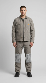 Mand i grå Carhartt-arbejdsjakke og bukser med knæbeskyttere mod en grå baggrund.