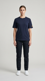 Kvinde iført mørkeblå t-shirt og matchende bukser med hvide sneakers mod en lys baggrund.