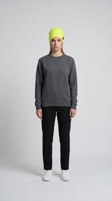 Kvinde iført grå sweatshirt, sorte bukser og en neongul hue mod en lys baggrund.