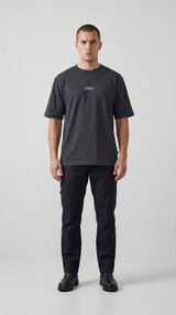 Mand i mørkegrå t-shirt, sorte cargobukser og sorte støvler mod en lys baggrund.