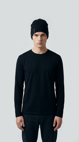 Mand i sort langærmet t-shirt og sort hue mod en neutral grå baggrund.