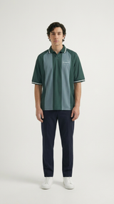 Mand i grøn og grå stribet polo, mørkeblå bukser og hvide sneakers på hvid baggrund.