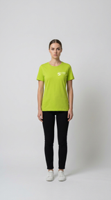 Kvinde iført limegrøn t-shirt med hvidt logo, sorte bukser og hvide sneakers mod en lys baggrund.