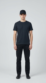 Mand i sort t-shirt, sorte jeans og sort kasket mod en lys baggrund.