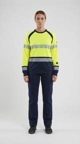Kvinde i gul high-vis sweatshirt med reflekser og navyblå arbejdsbukser mod en lys baggrund.