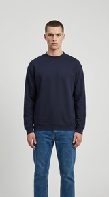 Mand iført en mørkeblå sweatshirt og blå jeans mod en ensfarvet grå baggrund.