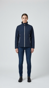 Kvinde iført mørkeblå softshell-jakke og blå jeans mod en lys grå baggrund.