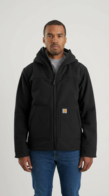 Mand i sort Carhartt-hættejakke og blå jeans mod en lys baggrund.