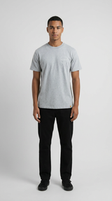 Mand i grå t-shirt og sorte bukser stående mod en lys grå baggrund.