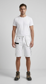 Mand i hvid t-shirt, hvide arbejdsshorts med lommer og brune arbejdsstøvler mod en grå baggrund.