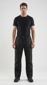 Mand i sort t-shirt og sorte outdoorbukser stående mod en hvid baggrund.