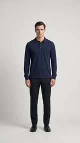 Mand i mørkeblå langærmet polo shirt og mørke bukser mod en lys grå baggrund.